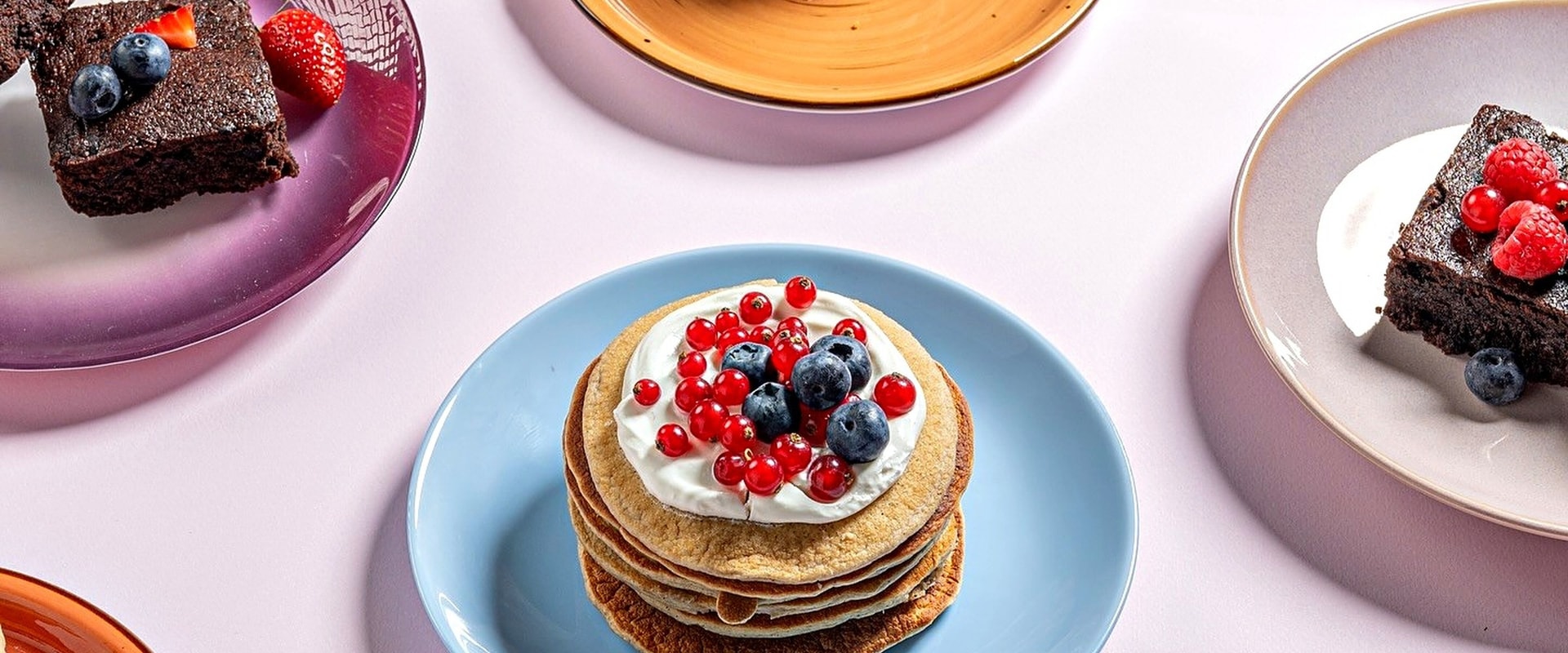Plates of pancakes and brownies with berries